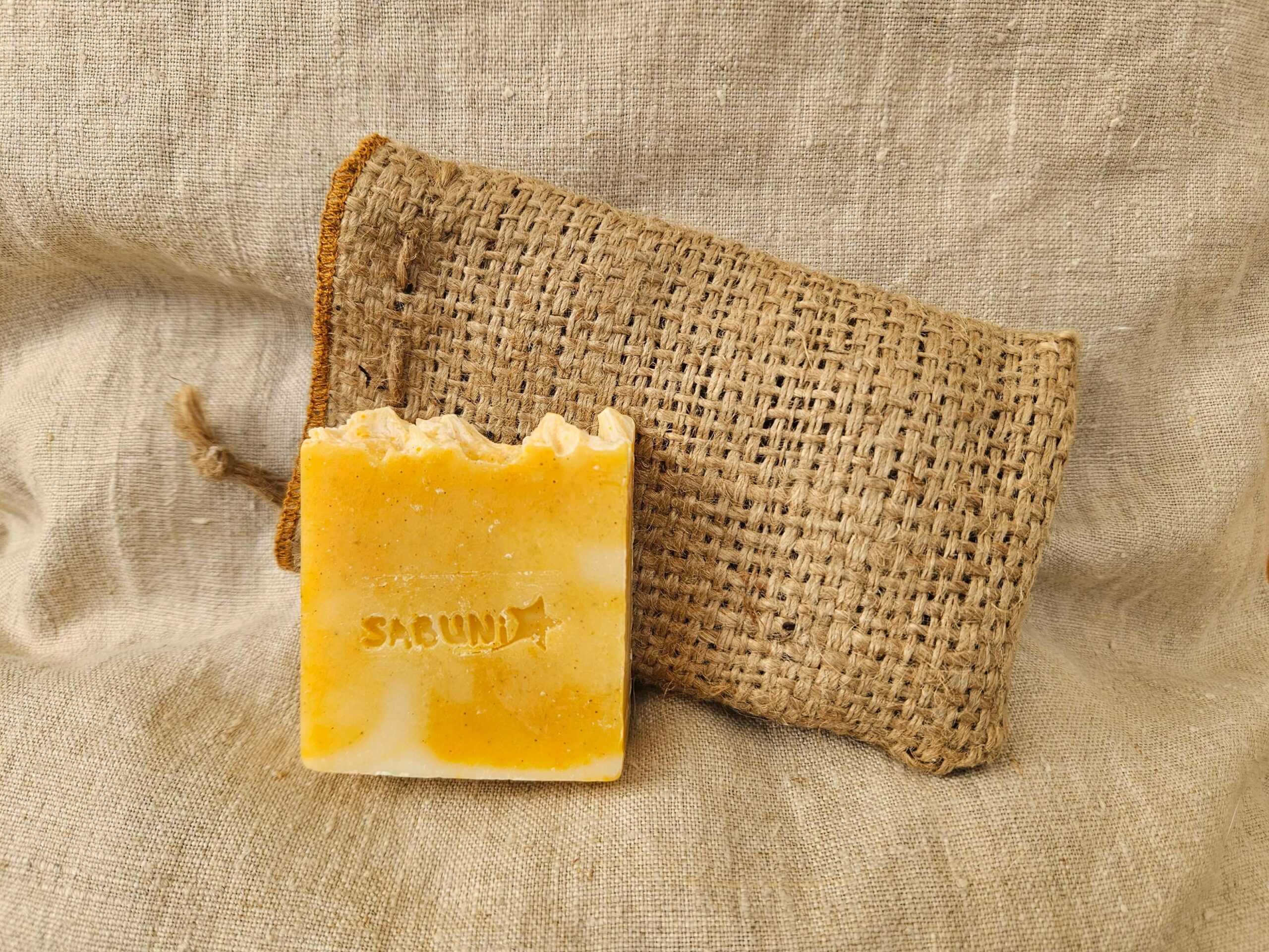 Accessoire zéro déchet de la savonnerie artisanale Sabuni & Cie. Sauve savon en toile de jute. Upcycling. Sauve savon sur fond en fibre naturelle.