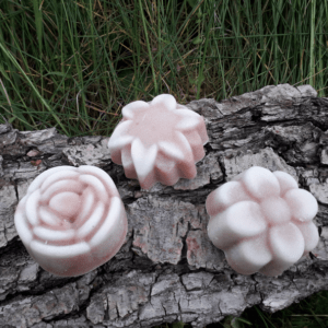 3 savons en forme de fleur posés sur une écorce