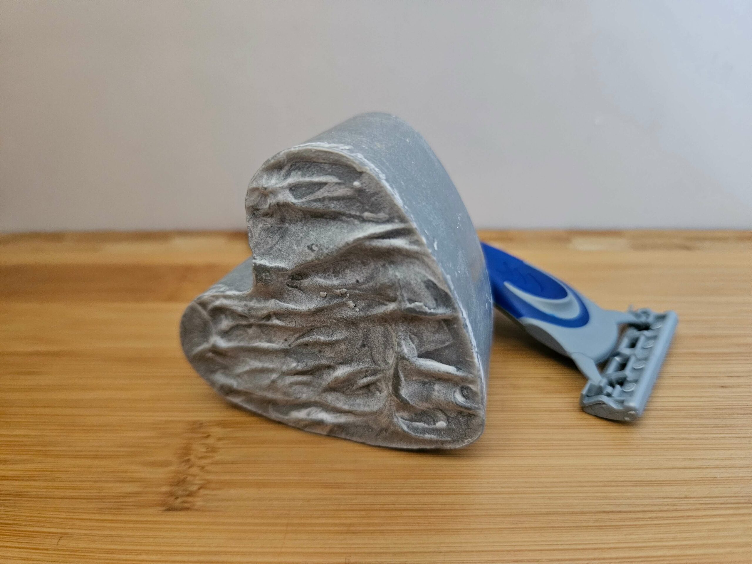 Savon à barbe ou de rasage. Savon artisanal surgraissé en forme de coeur, avec un rasoir posé sur le côté.