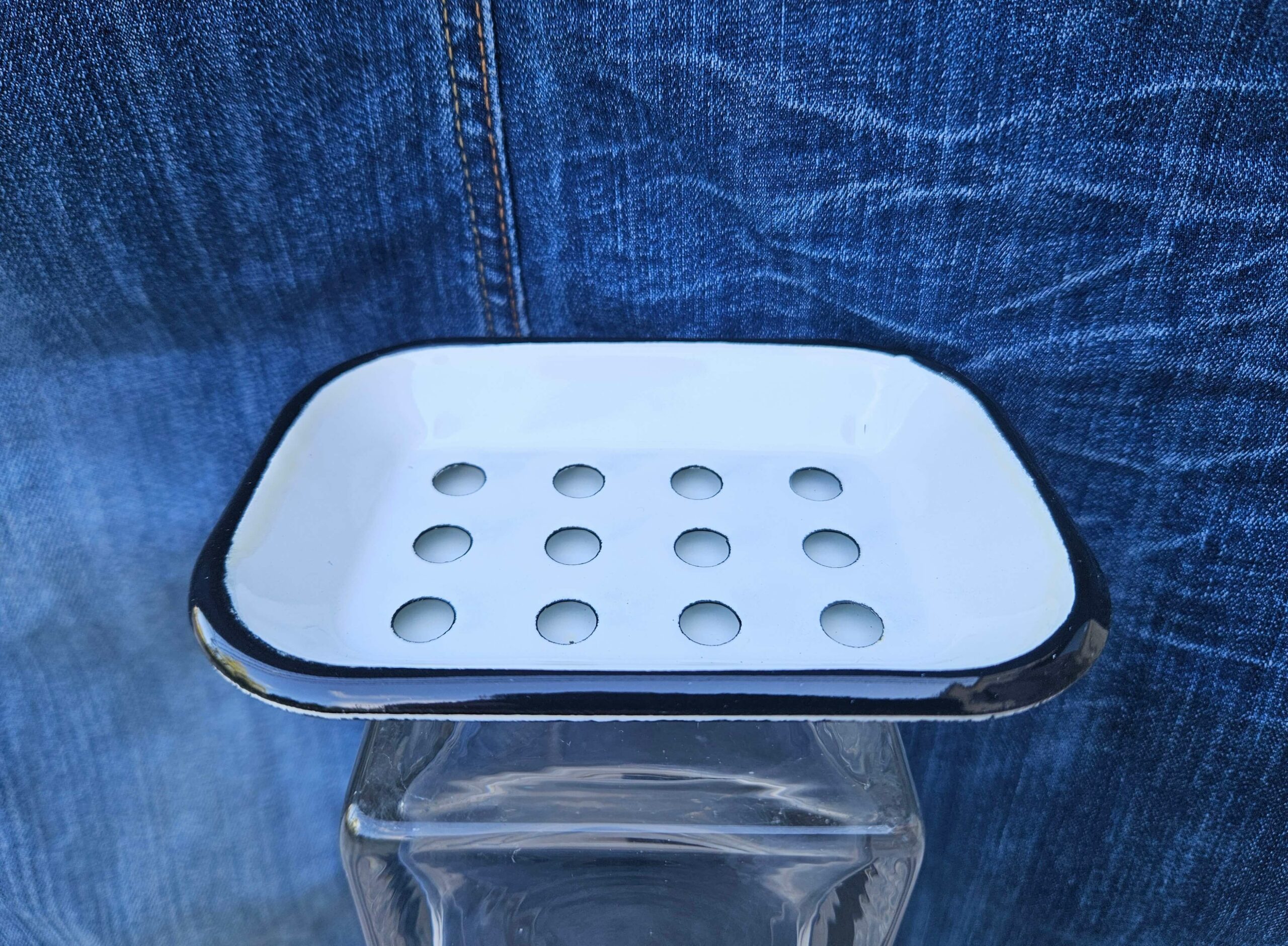 Accessoire zéro déchet de la savonnerie artisanale Sabuni & Cie. Porte-savon en fer émaillé fabriqué en Europe. Porte-savon en fer émaillé sur fond bleu jeans.